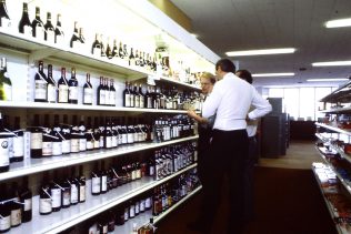 This is a Self Service Wines Layout Review discussion which would have also included wooden shelving behind Wines Counters in some older branches. The top shelf was at an almost unreachable height and required questionable access when moving bottles around during the review process by today's Health & Safety standards. | Merchandising Photo Library